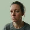 A person showing signs of dull, stressed skin on a soft green background